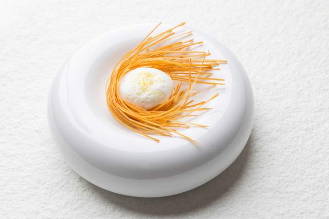 Dessert dressé en assiette blanche avec éléments filamenteux et crème du restaurant Køkken à Strasbourg