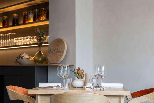 Table dressée dans la salle du restaurant Køkken à Strasbourg avec étagères en arrière-plan