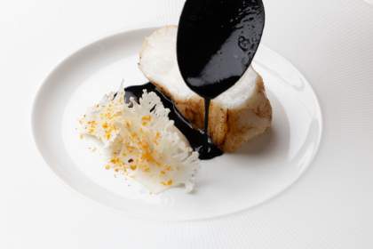 Sauce versée sur une noix de Saint-Jacques dressée en assiette blanche dans le restaurant Køkken à Strasbourg