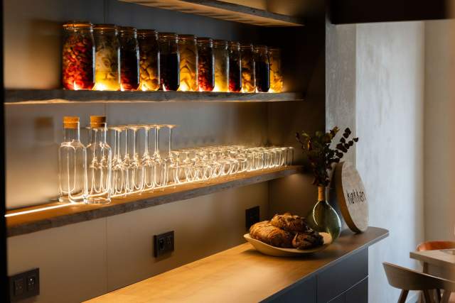 Étagères du restaurant Køkken à Strasbourg avec bocaux de fermentation, verres et pain